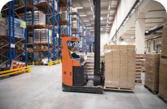 Warehouse employee storing pallet of boxes with forklift