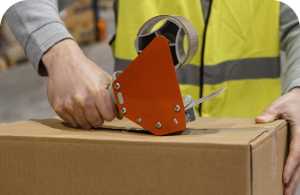 Warehouse employee sealing cardboard box for shipping